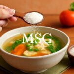 Bột ngọt MSG được rắc lên tô súp với rau củ và thịt, tạo vị ngon đặc trưng cho món ăn.